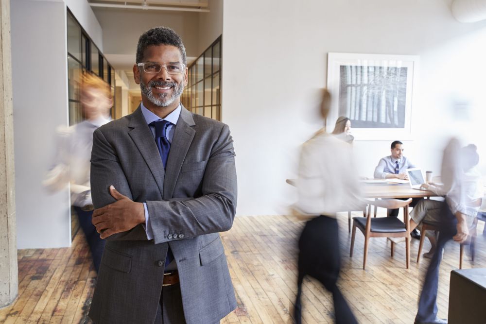 Portrait of middle aged black man in a busy modern workplace